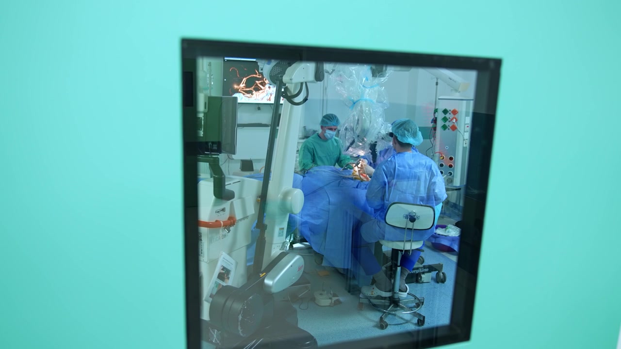 Equipo neuroquirúrgico realizando una cirugía en un quirófano bien equipado. Vista a través de la ventana de la puerta de una sala de cirugía.