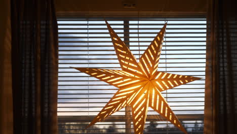 adorno de estrella de navidad brillantemente iluminado en la ventana, plano medio