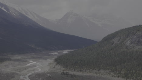 a serene valley beneath towering snowy mountain slopes