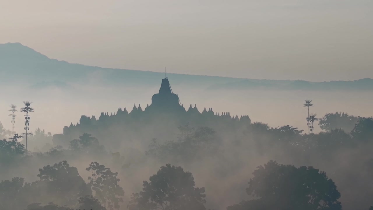 Tempio di Borobudur all'alba nebbiosa, scena naturale tranquilla con luce soffusa e monumento storico in Indonesia.