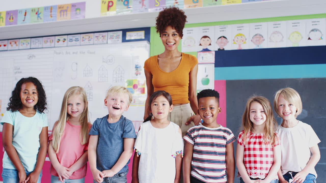 Portrait Of Elementary School Pupils Standing In Classroom With Female Teacher