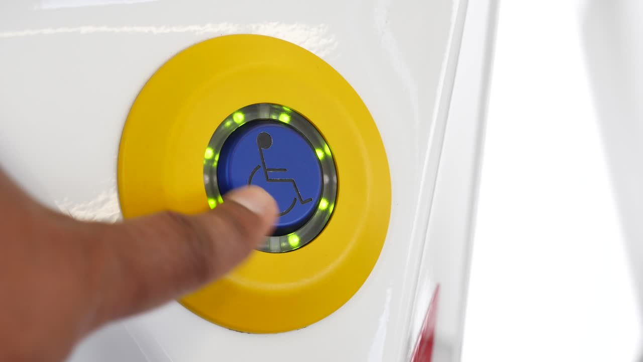 presionando con la mano un botón de acceso para silla de ruedas