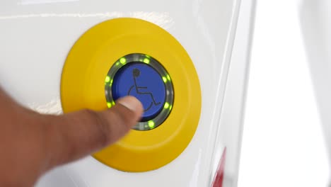 presionando con la mano un botón de acceso para silla de ruedas
