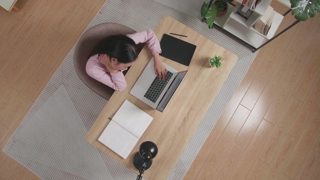 뷰  아웃  한 여성이 집에서 노트북에서 타이핑하는 나무 책상에 앉아 스트레칭