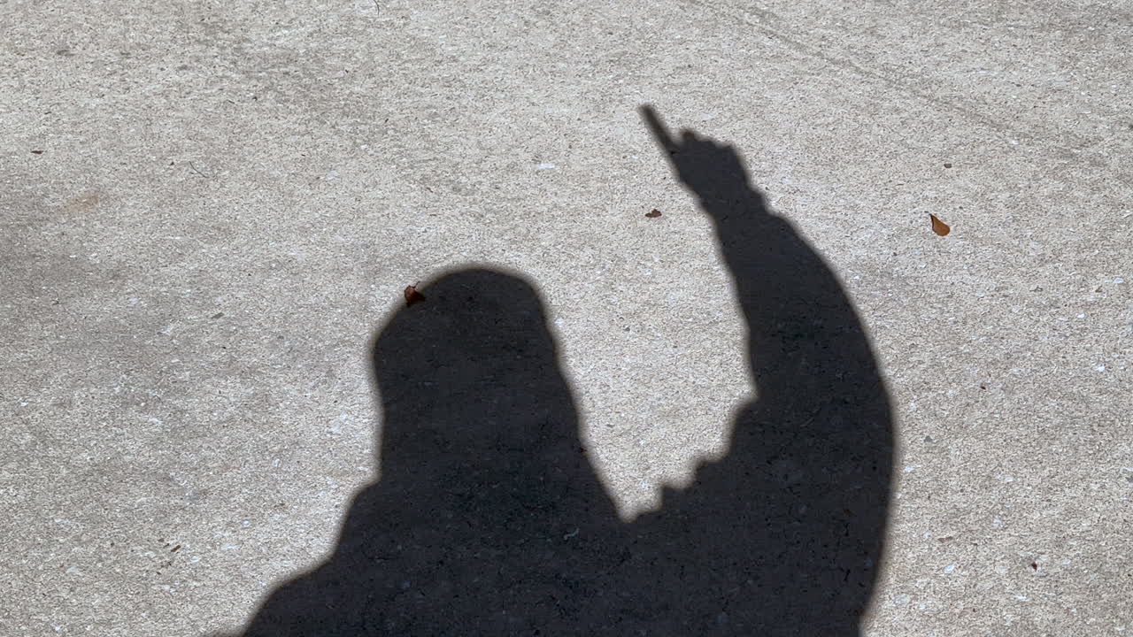 sombra del hombre que agita el número uno y el signo ganador con el dedo en la mano, hormigón