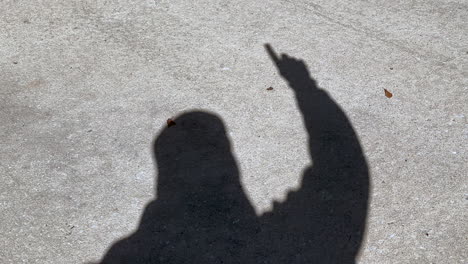sombra del hombre que agita el número uno y el signo ganador con el dedo en la mano, hormigón