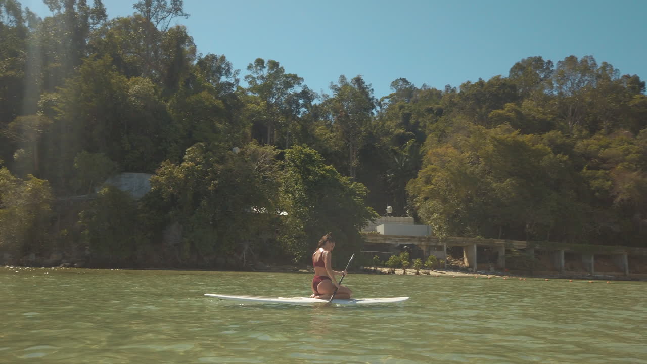 Una turista su stand up paddle pagaia nell'oceano al largo del Borneo.