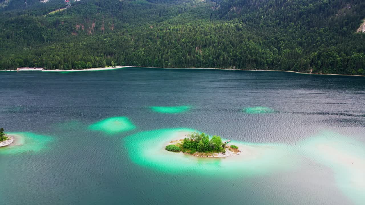 Aerial view of little islands in a luminescent lake, surrounded by wilderness of pine trees at the base of Zugspitze mountain