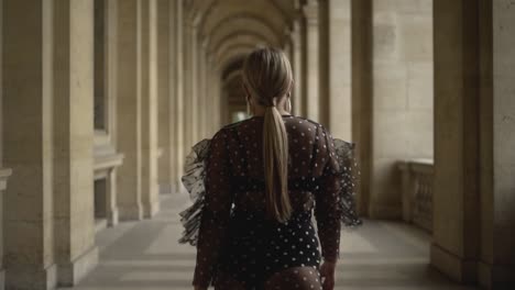 woman in a polka dot dress walking through parisian arcades