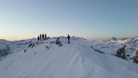 Drone-footage-of-a-man-walking-on-a-crest-with-snowshoes-and-his-friends-waiting-for-him-on-a-snowy-peak-near-the-Pic-du-Midi-D'Ossau