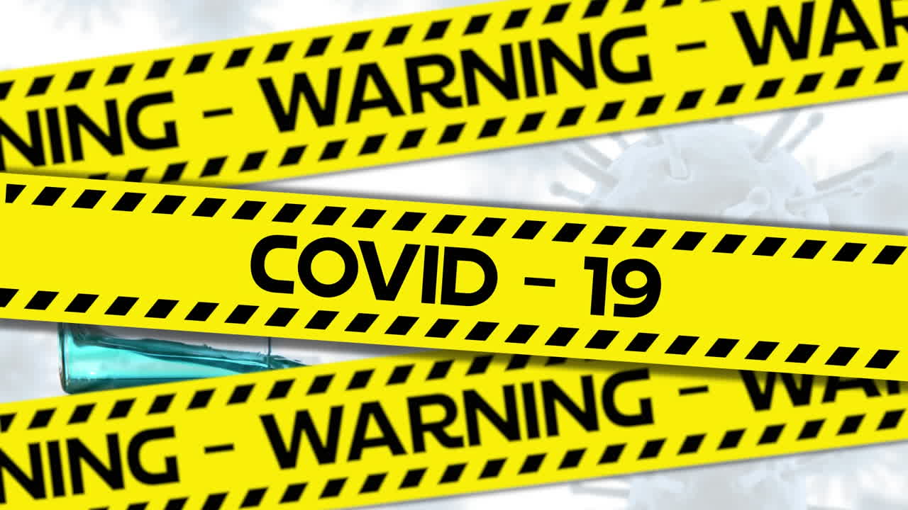 Words Warning Covid-19 written in black letters on yellow and black tape with Covid-19 spreading