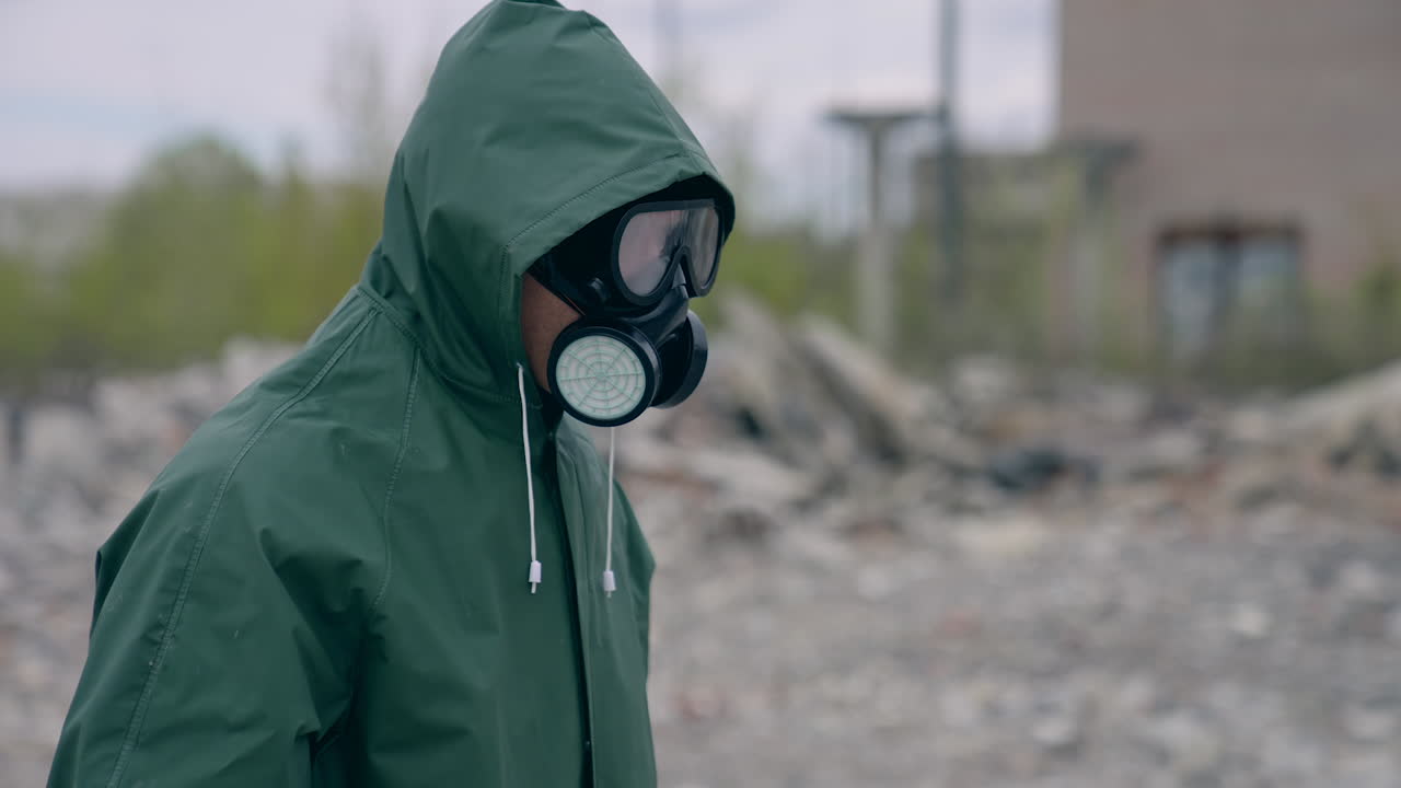 Man in chemical protection suit. Human in safety uniform and gas mask standing in abandoned place. Biological attack.