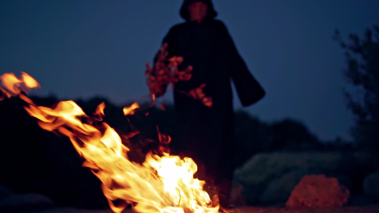 Scary witch conjures around the fire. A terrible ritual. Halloween. Horror.