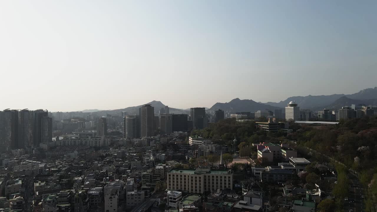 Aerial drone fly over Gangnam district in Seoul with mountain backdrop, South Korea