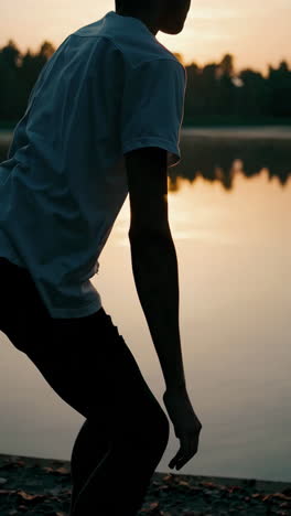 man sitting by a lakeside at sunrise