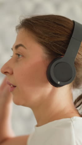 mujer toca auriculares mientras corre de cerca. mujer deportiva tiene una explosión con auriculares trabajando en la cinta de correr en el gimnasio. combatiendo el aburrimiento durante el ejercicio