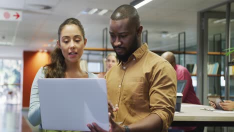 Diverse-male-and-female-business-colleagues-talking-and-using-laptop