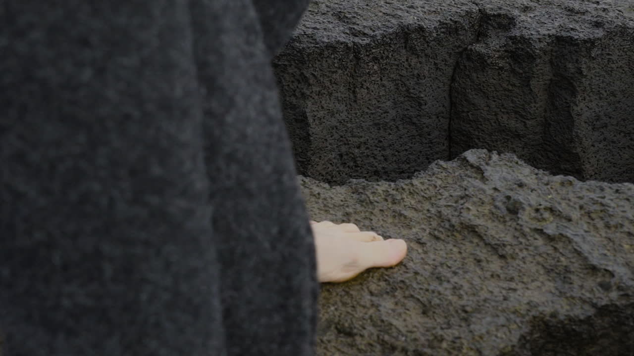 Close-up of woman's feet walking on wet cliffs