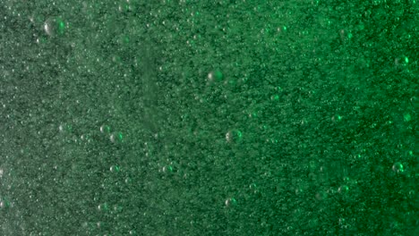 a variety of green and white bubbles rise through a liquid at different speeds