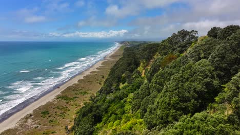 aerial unspoilt jagged coastline—turquoise waves crash against cliffs, windswept trees cling to edges, and sunlight flickers across the wild, untouched shore. drone new zealand native