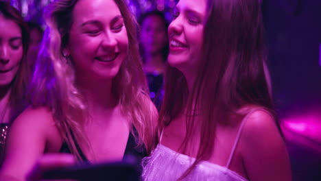 dos mujeres felices tomando una selfie en un club nocturno