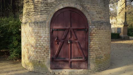 brick water tower against blue sky. old round tower with wooden door on lock.