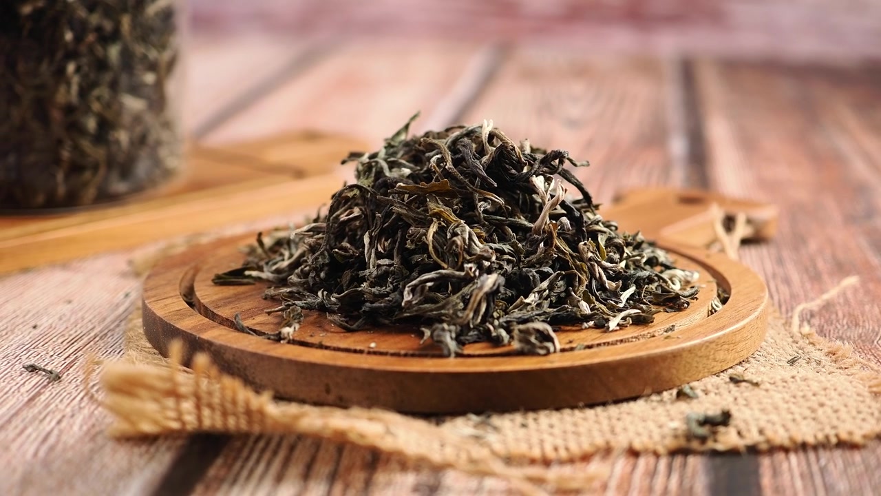 Foglie di tè verde essiccate su un tagliere di legno.