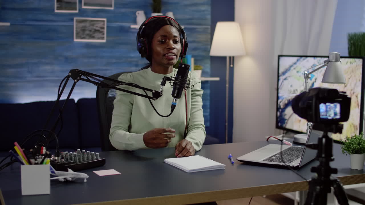 Black blogger sitting at home vlog station while video camera recording