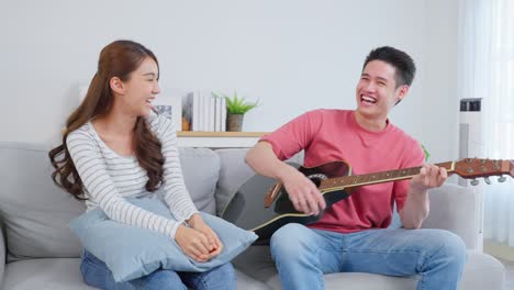 couple singing and playing guitar at home