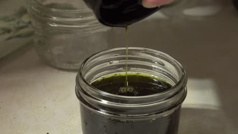 pouring green liquid from french press into glass mason jar