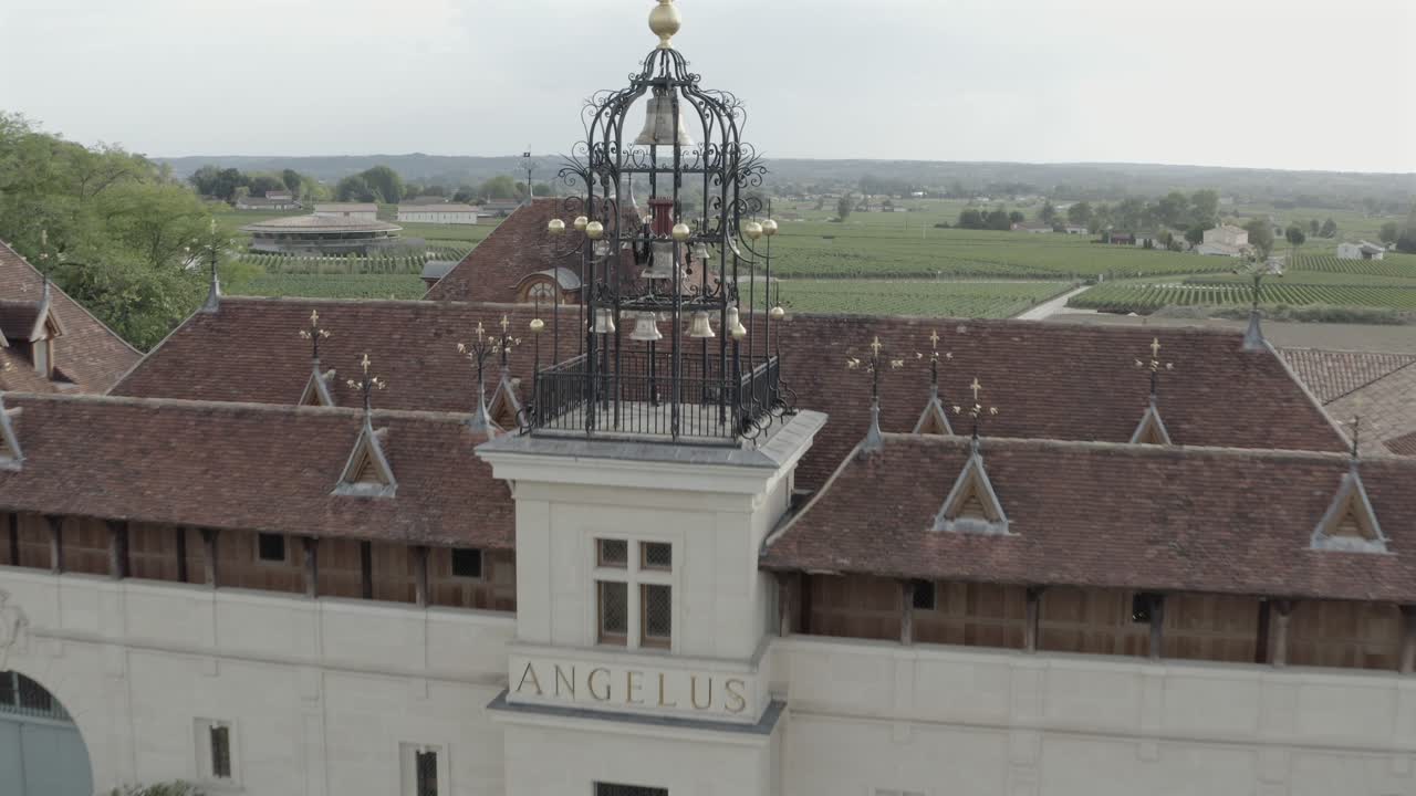 Aerial drone shot of the famous Château Angélus winery, showing the main facade, elegant courtyard, and iconic carillon. Prestigious estate in Saint-Émilion, France