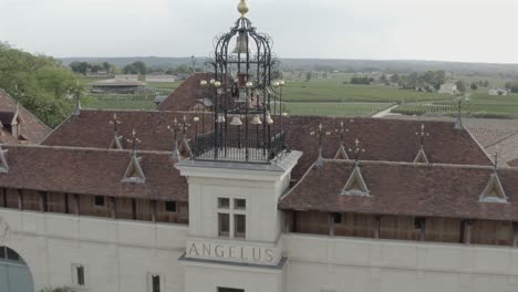 aerial drone shot of the famous château angélus winery, showing the main facade, elegant courtyard, and iconic carillon. prestigious estate in saint-émilion, france