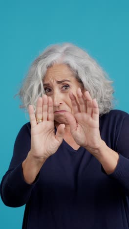 elderly woman showing fear or repulsion with hands raised