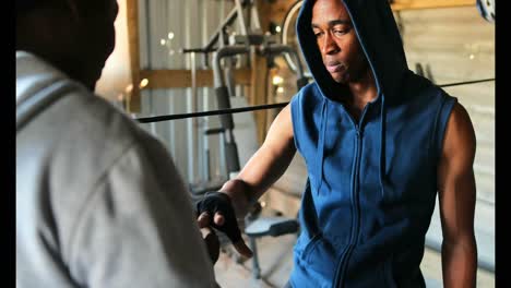 african american male trainer assisting boxer in wearing hand wrap in gym 4k