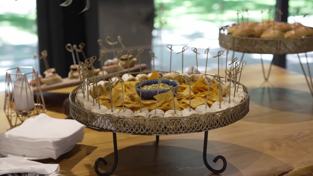 Stylish wedding appetizer table with nachos, dip, mini burgers, and canapés