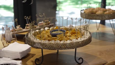 stylish wedding appetizer table with nachos, dip, mini burgers, and canapés