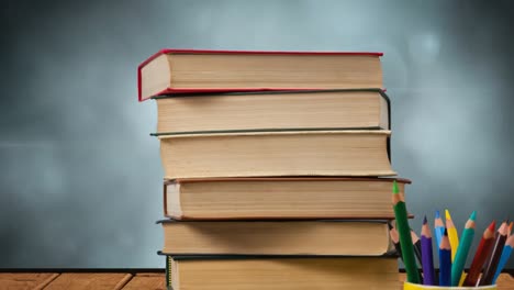 animación de una pila de libros junto a una taza con lápices de colores sobre luces brillantes