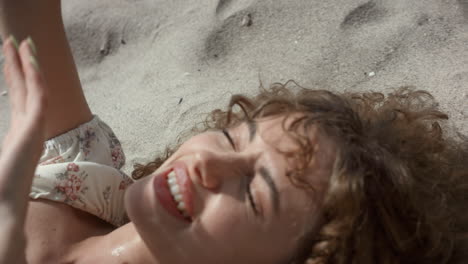 laughing cheerful girl hiding from sun with hands close up. woman lying on sand.