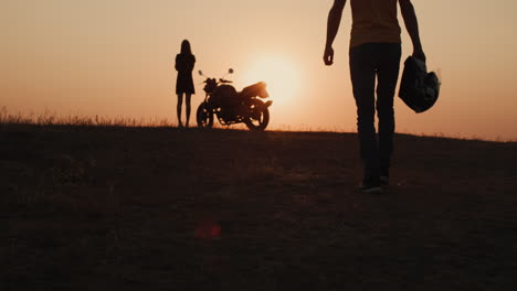 the silhouette of a man walking to his motorcycle
