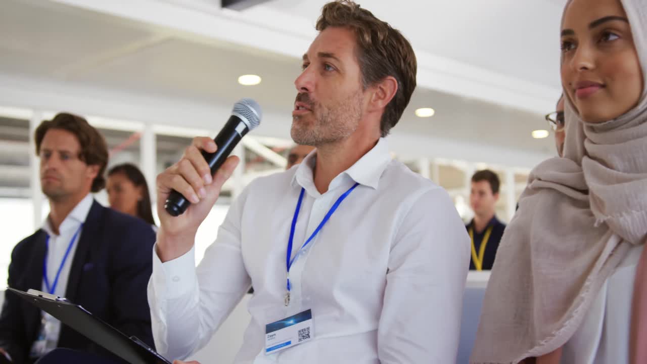 miembro de la audiencia masculina en una conferencia de negocios haciendo una pregunta