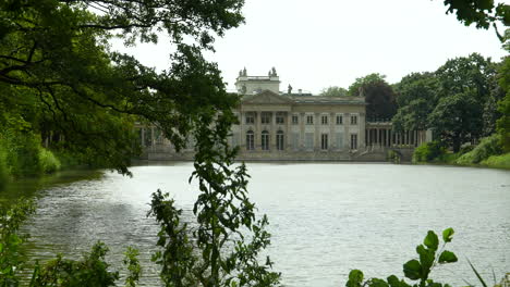 el palacio en la isla en varsovia - un palacio neoclásico real junto al lago, enmarcado por árboles exuberantes, que refleja la tranquilidad y la elegancia histórica