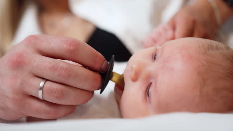dad's hand giving a pacifier to a newborn. baby takes a pacifier and starts to sick it. close up.
