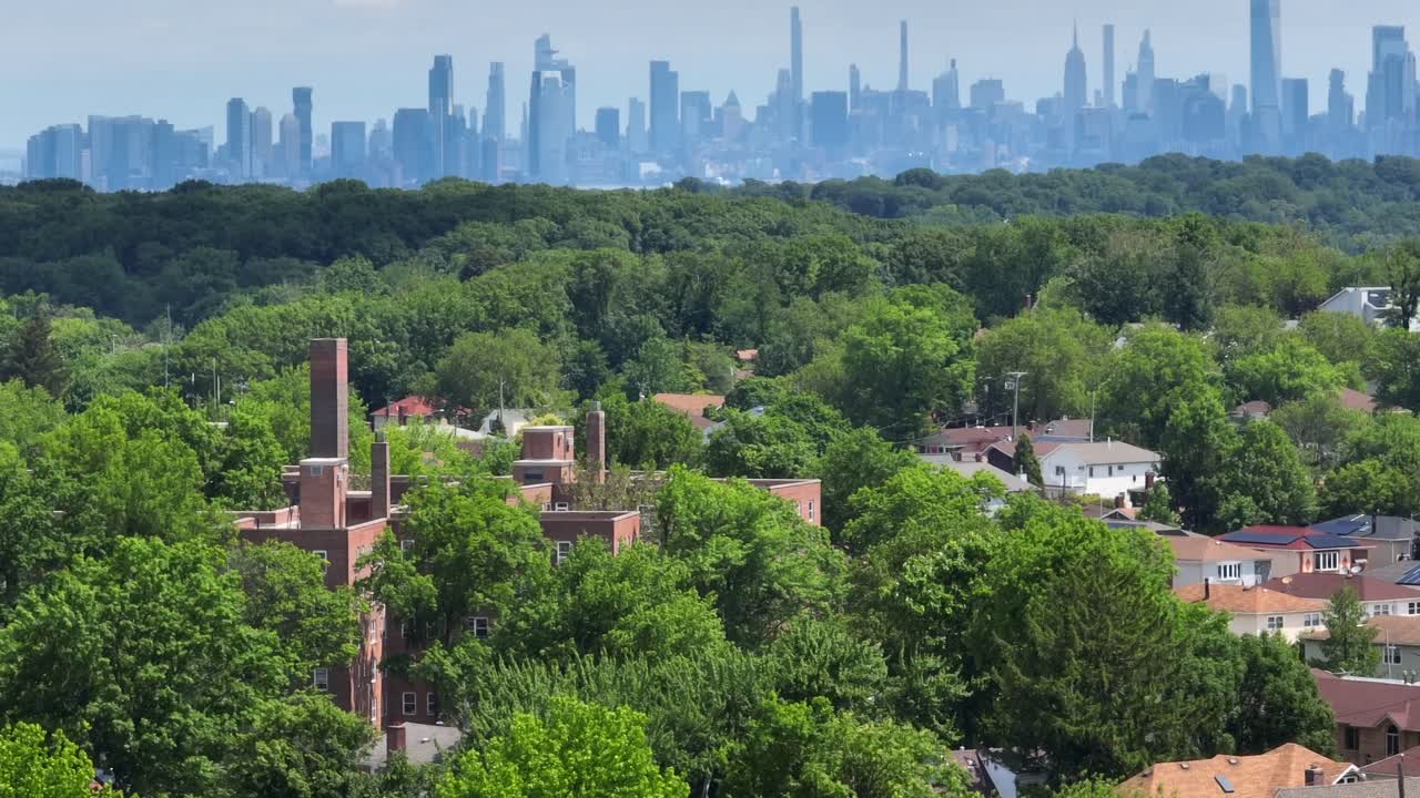 Aerial tilt up showing dense Staten Island Greenbelt Park and gigantic skyline of Manhattan NYC in background