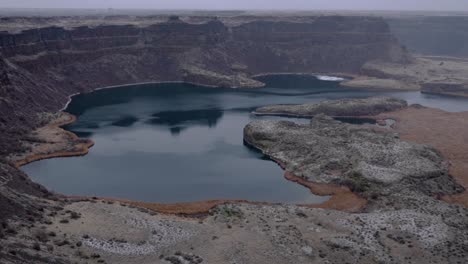 Winter-footage-of-Dry-Falls-lake,-pans-up-to-baslt-cliffs