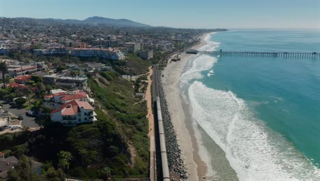 aerial view of an amtrak train moving along side the pacific ocean near san clemente, california