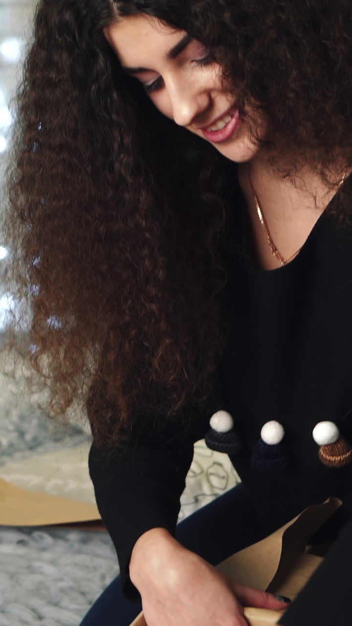Girl packing gift. Young beautiful woman wraps Christmas gifts while sitting on bed Vertical video