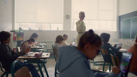 Female-teacher-and-students-with-digital-tablets-having-lesson-in-classroom