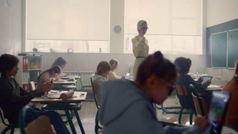 maestra y estudiantes con tabletas digitales dando clases en el aula