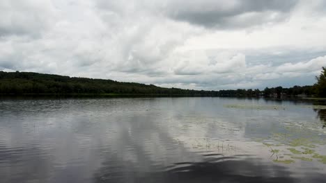 aerial flyover jetty and natural lake in quebec surrounded by nature during clouds at sky