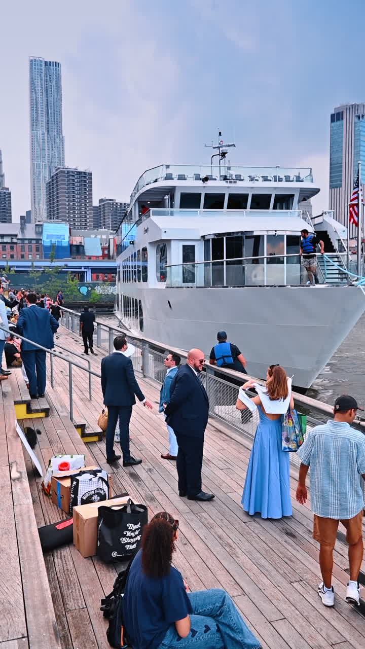 New York, USA, 8 July 2025: Enjoying a riverboat arrival in New York. A group waits at the dock as a riverboat approaches the pier in New York City during a cloudy day